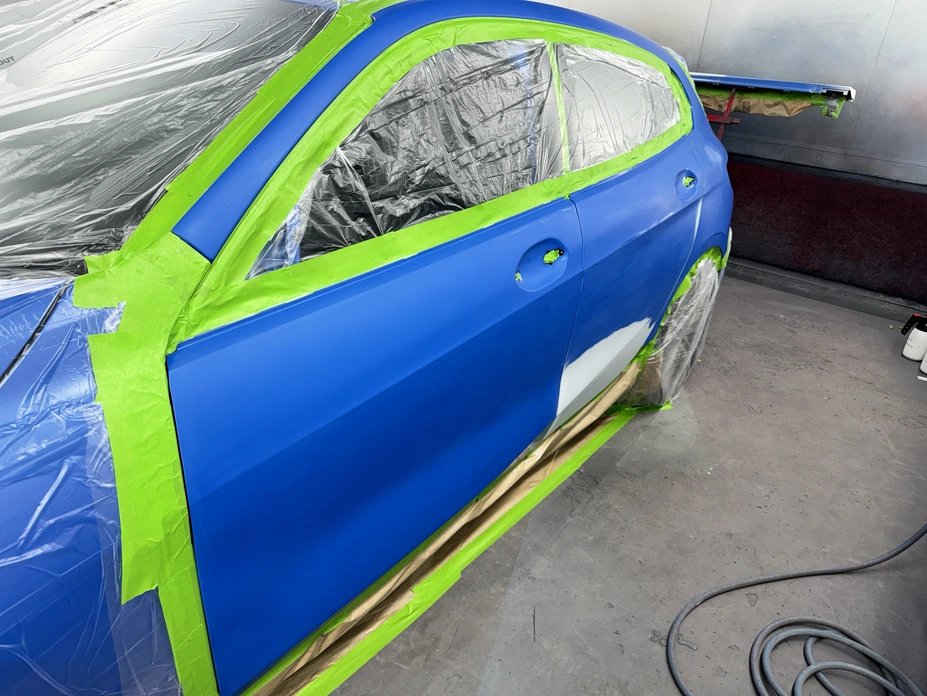 Car side covered with protective film, painted in vibrant blue